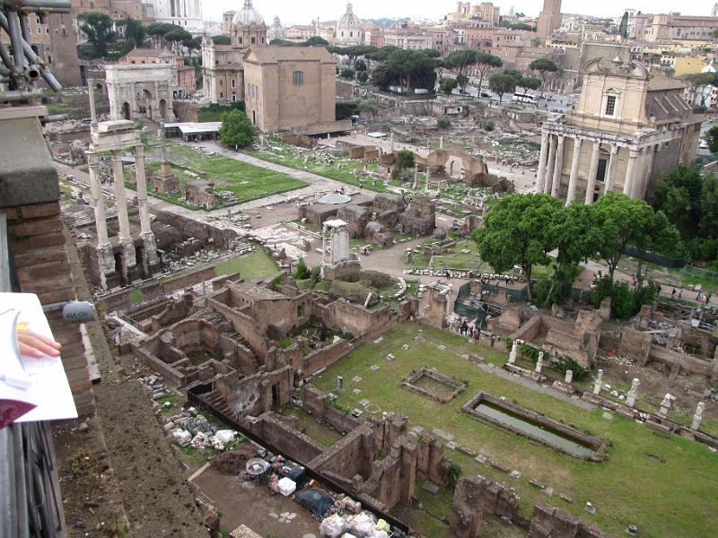 forum romanum_vanaf_palatijn.jpg - Overzicht van het Forum Romanum vanaf het Palatijn. Links de drie zuilen van de tempel van Castor en Pollux. Achteraan links de boog van Septimius Severus. Het grote rechthoekige gebouw rechts van de triomfboog is de Curia Julia, het senaatsgebouw van het oude Rome.Rechtsboven (het gebouw met de zuilen) staat de tempel van Antoninus en Faustina. De twee bassins rechtsonder horen bij het huis van de Vestaalse Maagden.